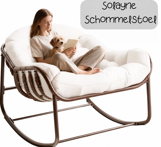 Een vrouw met een hond leest een boek in de Solayne schommelstoel, wit met rotan zijkanten.