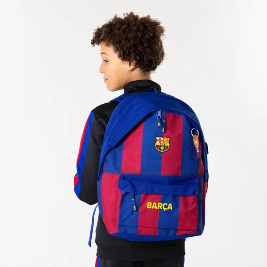 Jongen draagt blauwe rugzak met rode strepen, FC Barcelona logo en 'Barça' tekst.