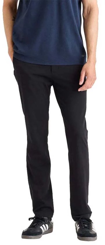 Man in zwarte chino broek met t-shirt, staand.