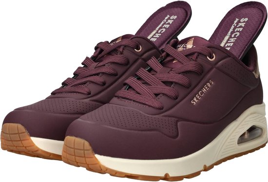 Paarse Skechers sneakers met beige zolen, gouden accenten en zichtbare luchtdemping.