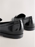 Zwarte lakleren loafers met zilverkleurige gespen, detail van de hak.