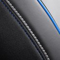 Close-up van zwarte autostoelhoes met ruitpatroon, blauwe en witte stiksels.