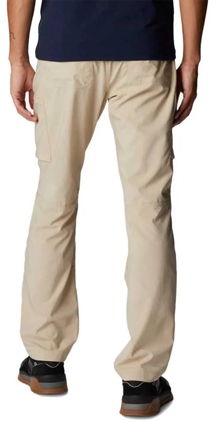 Man in beige cargo broek, staand, achterkant. De broek heeft een trekkoord en cargozakken.