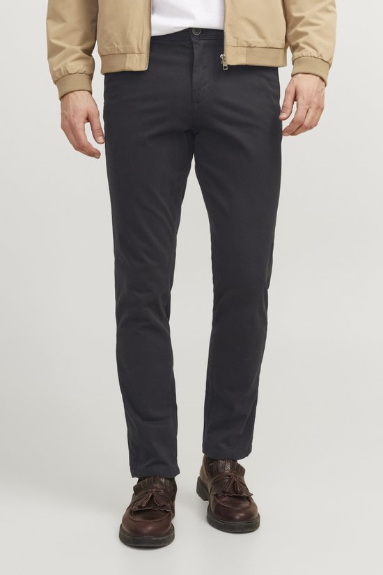 Man die een zwarte chino draagt, met een beige bomberjack.