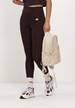 Dames Adidas legging in bruin met een zakje op de heup. De legging heeft witte Adidas strepen op de linkerheup.