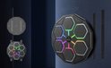 Octagonale bokstrainer met 6 led-panelen, gemonteerd aan een muur. Achterkant van de trainer en muurbevestigingsstrips worden getoond.