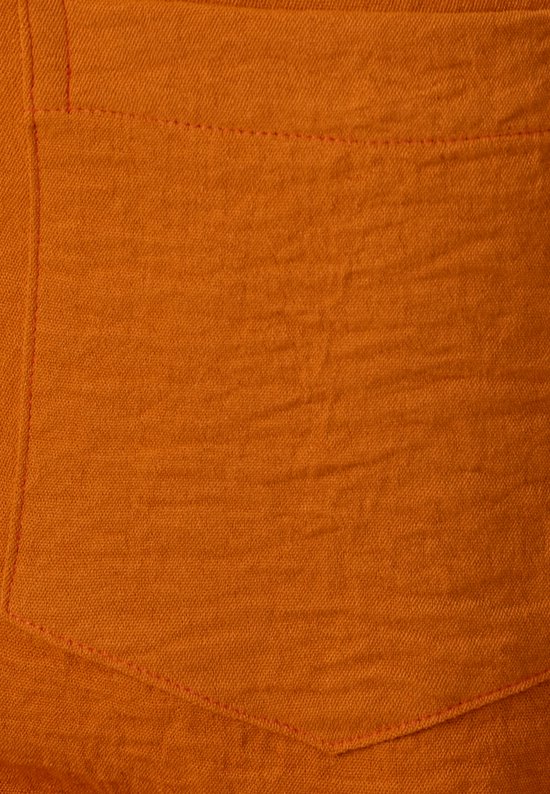 Detail van oranje blouse: borstzakje met zichtbare, roze stiksels.