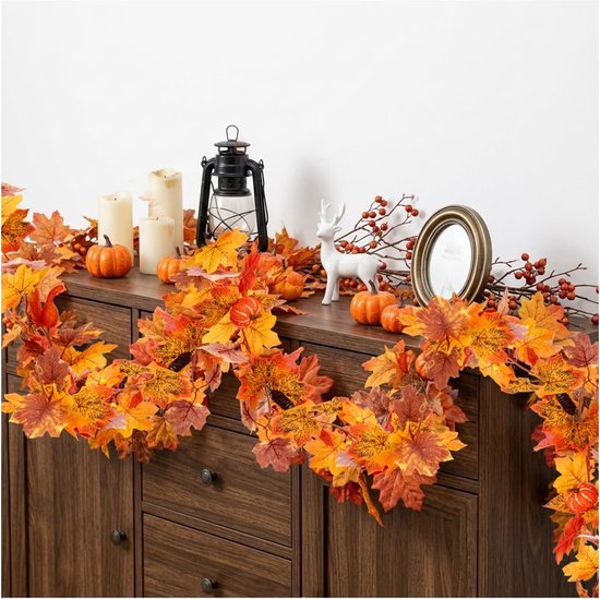 Herfstbladerenslinger met pompoenen en decoraties op een kast.