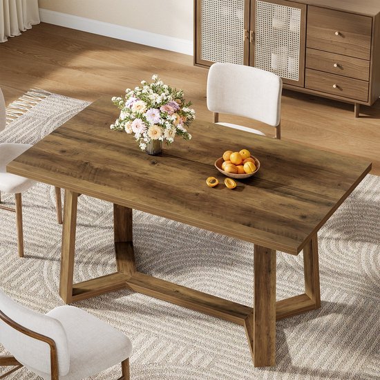 Eettafel met houtlook blad, bruine houten poot. Gedekt met fruit en bloemen.