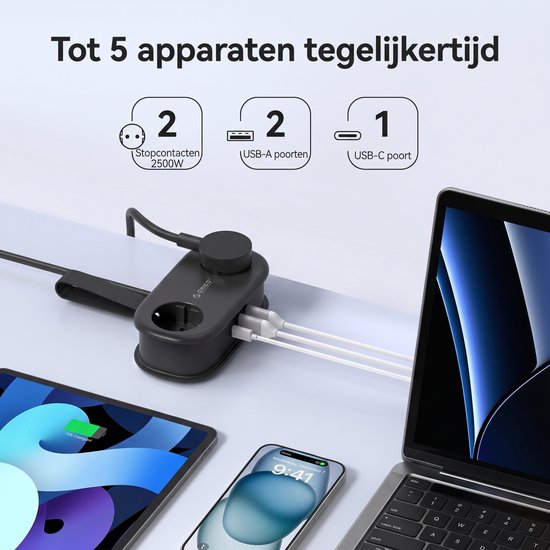 Zwarte stekkerdoos laadt 5 apparaten tegelijk op: 2 stopcontacten (2500W), 2 USB-A poorten en 1 USB-C poort. Laptop, tablet en smartphone opgeladen.