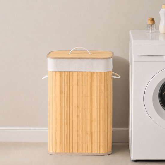 Bamboe wasmand met deksel naast een wasmachine in een moderne badkamer.
