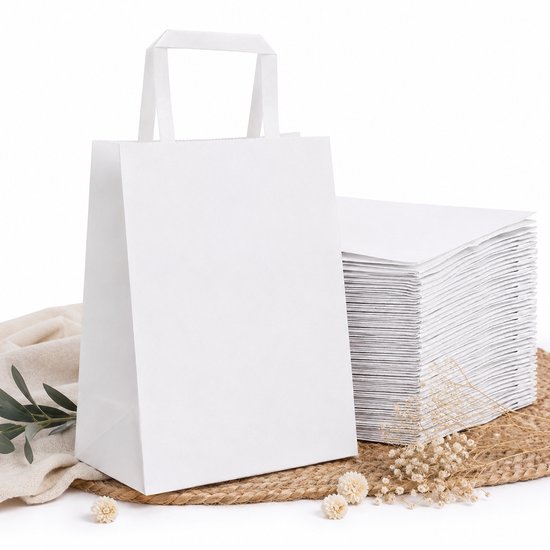 Witte papieren draagtas met platte handgrepen op een rieten ondergrond, naast een stapel tassen.