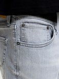 Close-up van de zakken van een grijze denim jeans met knopen en metalen studs.