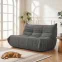 Grijze vloersofa met zachte bekleding, een slapende kat op een kleed ervoor.