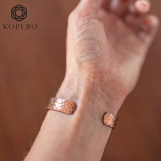 Koperen armband met gehamerde textuur, detailopname van het uiteinde bij de pols. Kopero logo in de hoek.