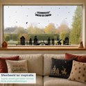 Raamdecoratie Sinterklaas: zwart silhouet van een stadsgezicht met huizen, molen en brug, met de tekst "Welkom Sinterklaas". Sterren en maantjes op het raam.