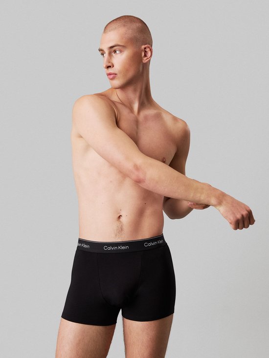 Model draagt zwarte Calvin Klein boxerbriefs met een logo op de tailleband.