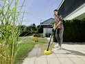 Vrouw met een Kärcher hogedrukreiniger met gele terrasreiniger, schoonmaken op een terras.