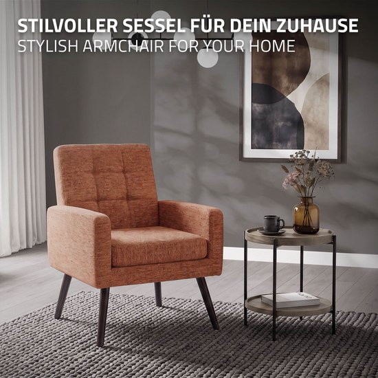Stijlvolle oranje fauteuil met armleuningen en capitonnering, op donkere poten, in een woonkamer.