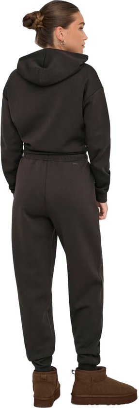 Vrouw met opgestoken haar, van achteren gezien, draagt een donkerbruine hoodie en bijpassende joggingbroek.