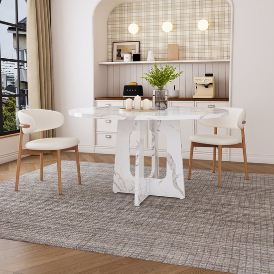 Ronde marmerlook eettafel met vier witte stoelen met houten poten.