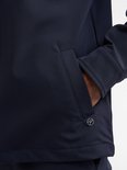 Detail van de zijnaad met zak van een donkerblauw jack, met logo.