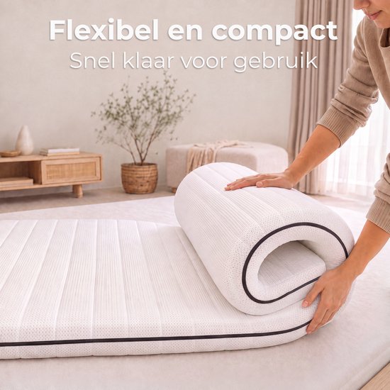 Hand rolt een wit matras op, compact en klaar voor gebruik.