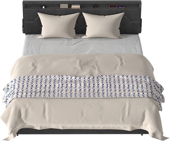 Grijze gestoffeerde hoofdbord met opbergvakken, boven een bed met wit beddengoed en een beige plaid met geometrisch patroon.