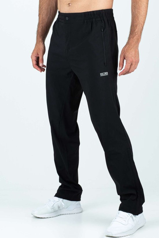 Zwarte sportbroek met logo op de zijkant, gedragen door een man met witte sneakers.