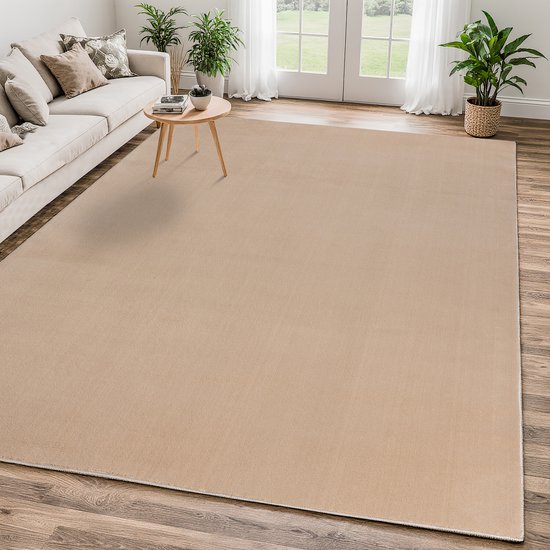 Een ruim, beige vloerkleed in een woonkamer met een bank en salontafel.