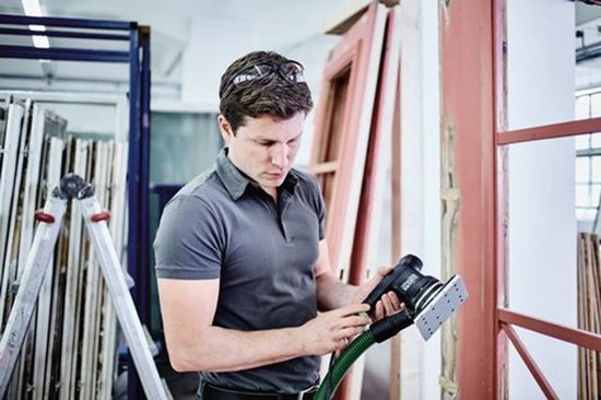 Man in werkplaats houdt een Festool RTS 400 REQ schuurmachine vast.