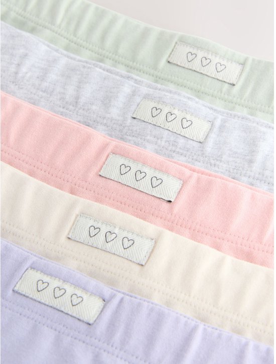 Close-up van de elastische taillebanden van 5 shorty's met elk een label met drie hartjes.