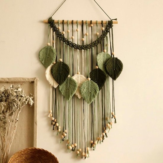 Macramé muurhanger met bladvormen in saliegroen en crème, gedetailleerd met houten kralen en een gevlochten rand.