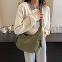 Groene corduroy crossbodytas gedragen door een model, met gedetailleerde ritssluitingen en verstelbare band.