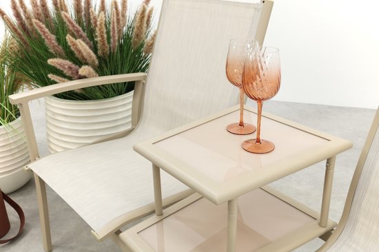 Twee roze wijnglazen op een beige bijzettafel tussen twee tuinbanken.