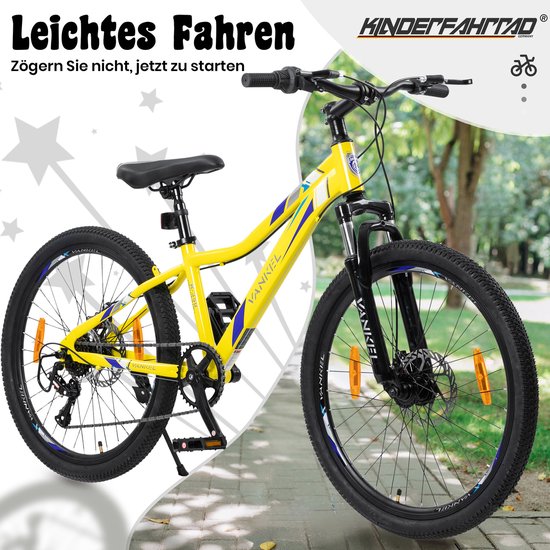 Gele mountainbike met zwarte en blauwe details, 24 inch wielen en verende voorvork, op een pad met groen gras.