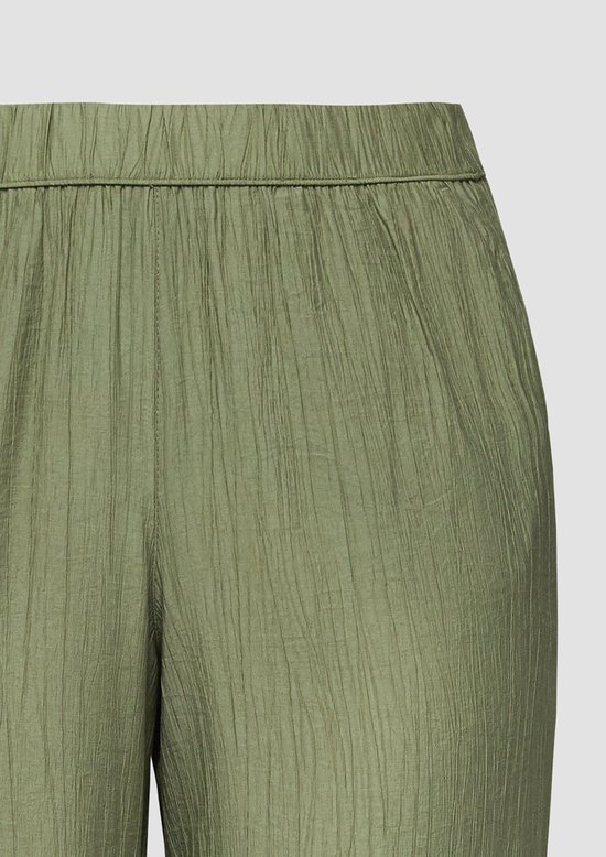 Detail van een olijfgroene broek met elastische tailleband en crinkle stof.