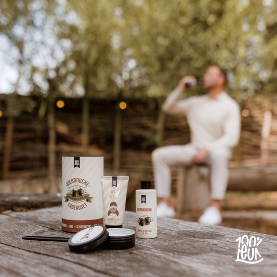 Cadeauset van 100% LEUK staat op een houten tafel, man drinkt op de achtergrond.