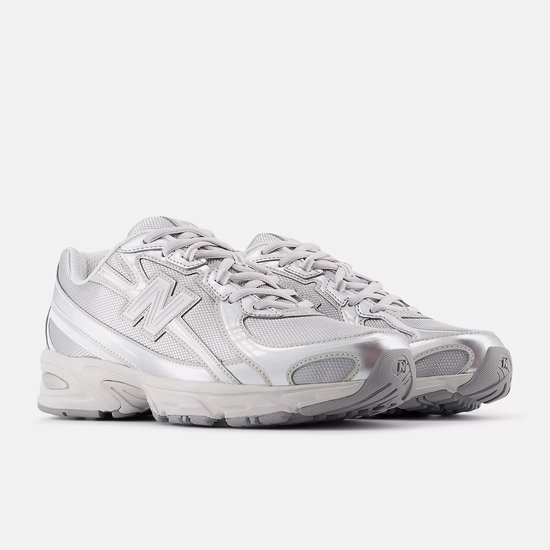 Twee lichtgrijze New Balance 740 sneakers met metallic zilveren accenten.