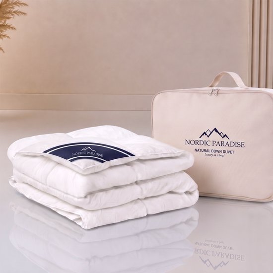 Een wit, gevouwen dekbed met Nordic Paradise logo, naast een beige opbergtas met hetzelfde logo.