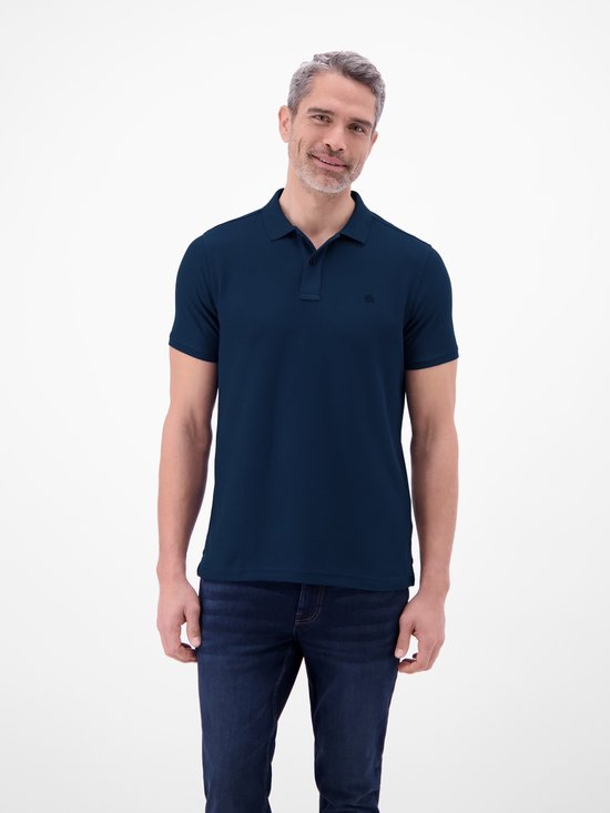 Man in donkerblauw poloshirt met korte mouwen, staand op een witte achtergrond.