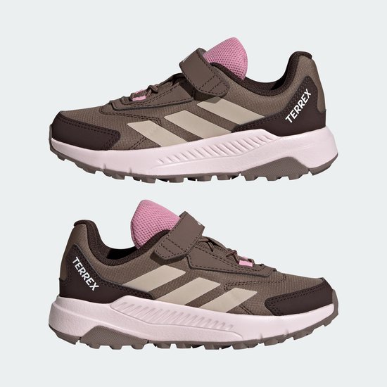 Twee bruine Terrex sportschoenen met roze accenten, beige strepen en klittenband.