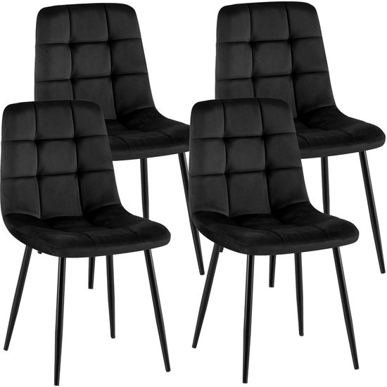 Set van vier zwarte fluwelen eetkamerstoelen met gewatteerde zittingen en slanke metalen poten.