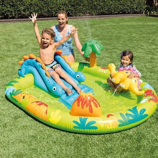 Een gezin geniet van een opblaasbaar dinosauruszwembad met glijbaan en fontein in de tuin.
