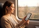 Een vrouw kijkt naar haar PocketBook Era Lite terwijl ze in een trein zit.