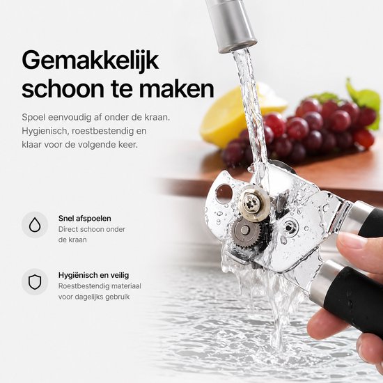 Roestvrijstalen blikopener met zwarte handgrepen onder de kraan, met druiven en citroen op de achtergrond.