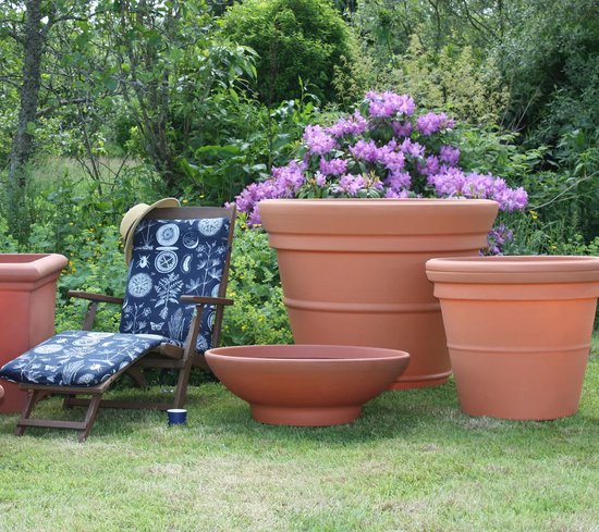 Zetel, tuinpotten van terracotta en een rode ligstoel met blauw kussen in de tuin.