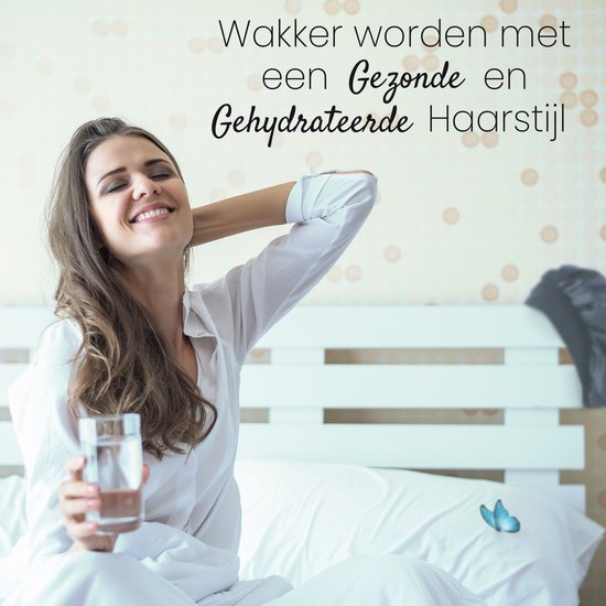 Een lachende vrouw met lang bruin haar, zittend op een bed, met een glas water.