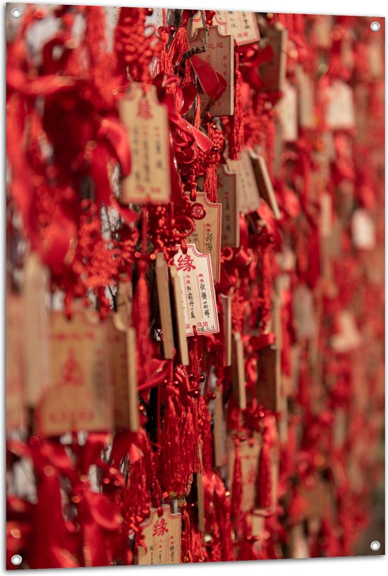 Tuinposter – Rode Sleutelhangers met Chinese Tekens aan een Muur - 80x120 cm Foto op Tuinposter (wanddecoratie voor buiten en binnen)