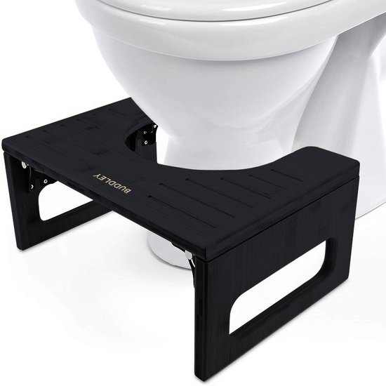 Zwart bamboe toiletkrukje met uitsparing, naast een toilet.